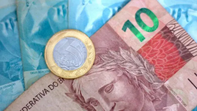 Notas de cem reais junto com uma nota de dez reais e uma moeda de um real para pagar o salário mínimo.