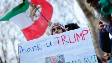 Manifestantes seguram a antiga bandeira nacional e cartazes em apoio a Reza Pahlavi durante protesto contra o regime em frente à Embaixada do Irã em Londres
