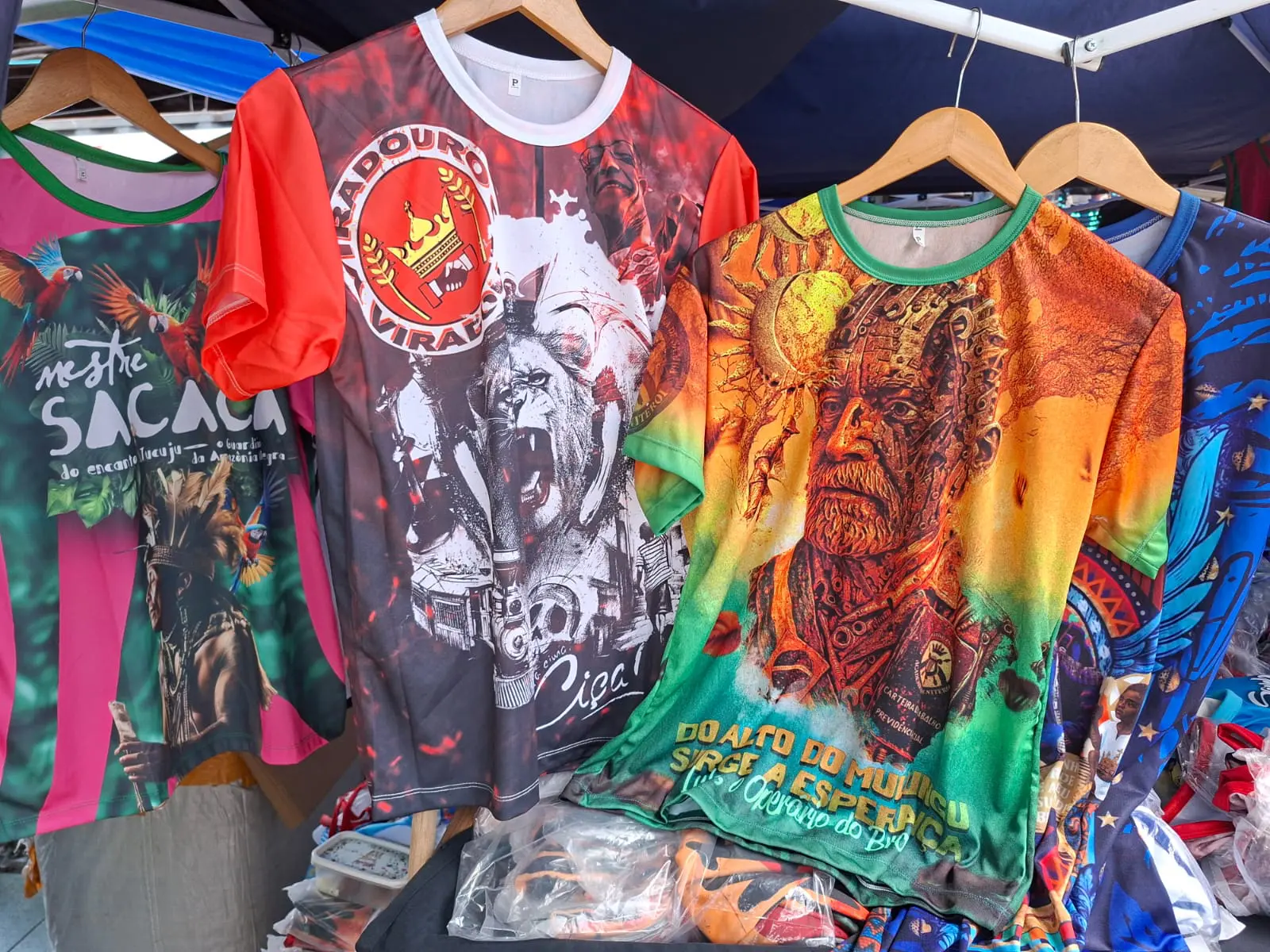 Lula é retradado com rosto de engrenagens em camiseta (à dir.) da escola de samba Acadêmicos de Niterói